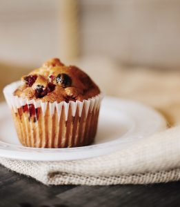 Cranberry muffin placed on a white dish on top of a beige cloth